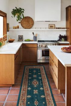 a kitchen with an area rug in the middle and wooden cabinets on both sides, along with white counter tops