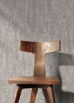 a wooden chair sitting in front of a wall with an artistic pattern on the wall