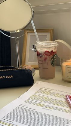 a starbucks drink sitting on top of a table next to a bag and some papers