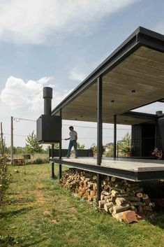 a man standing on top of a wooden deck next to a pile of rocks and grass