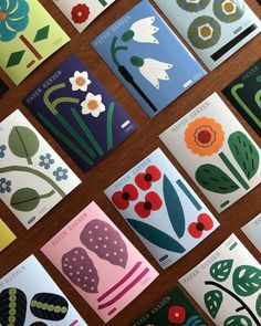 many different cards with flowers on them sitting next to each other in front of a wooden table