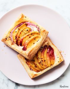 two pieces of pastry on a plate with some fruit in the middle and black pepper sprinkled on top