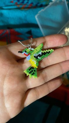 a hand holding a small green and yellow beaded keychain in it's palm