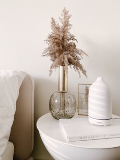 a white table topped with a vase filled with flowers and a book on top of it