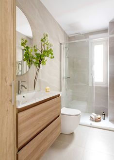 a white toilet sitting next to a wooden cabinet in a bathroom near a shower stall