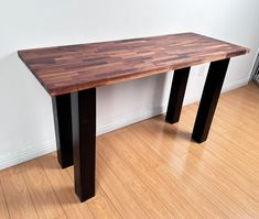 a wooden table sitting on top of a hard wood floor next to a white wall