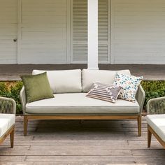 a couch and two chairs sitting on a wooden deck with shutters in the background