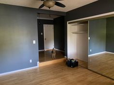 an empty room with hard wood flooring and a dog standing in the doorway looking at it