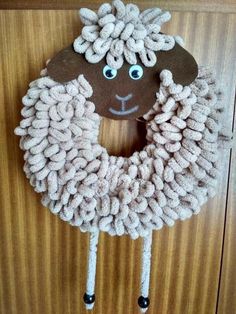 a door hanger made to look like a sheep's head with yarn on it