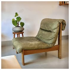 a chair with a pillow on it next to a potted plant