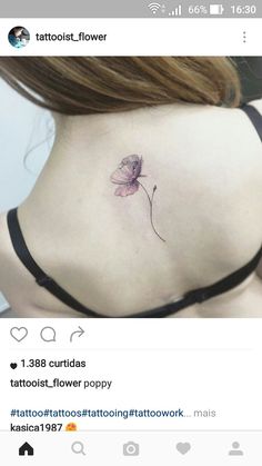 a small flower tattoo on the back of a woman's upper back ribcage