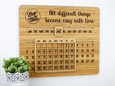 a wooden calendar hanging on the wall next to a potted plant