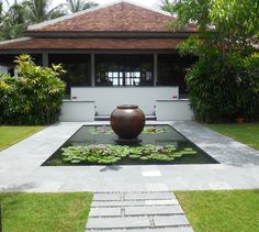 a large vase sitting on top of a pond in the middle of a lush green yard