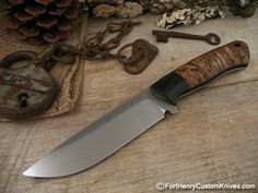 a large knife sitting on top of a wooden table next to some old rusty keys