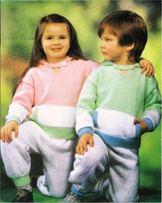 two young children sitting next to each other wearing matching sweaters and sweatpants,