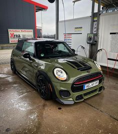 a green mini cooper parked in front of a gas station