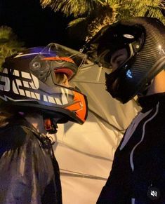 two people standing next to each other with helmets on their heads and palm trees in the background