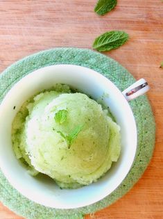 a bowl filled with green ice cream on top of a wooden table