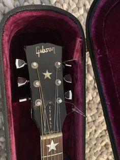 an acoustic guitar is in its case on the carpeted floor, and it's ready to be played