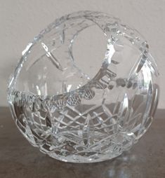 a clear glass bowl sitting on top of a wooden table next to a white wall