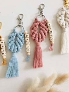 four keychains with tassels hanging from them on a white surface next to feathers