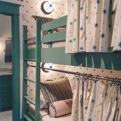 a bunk bed in a room with green walls and curtains on the wall, next to a mirror