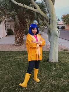 a woman with blue hair and yellow rain boots standing in front of a palm tree