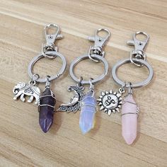 four key chains with charms on them sitting on a wooden table next to each other