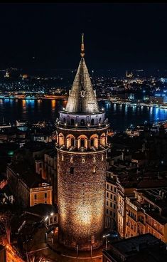 an aerial view of a city at night with the lights on and water in the background