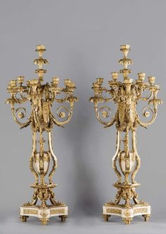 two golden candelabras with candlesticks on stands