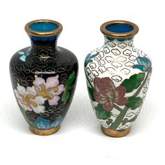 two vases with flowers painted on them sitting next to each other