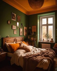 a bedroom with green walls and pictures on the wall above the bed is lit by candles