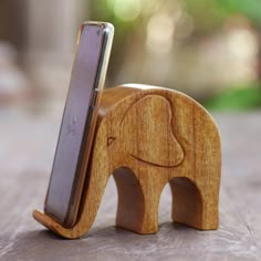 a wooden elephant with a cell phone in it's trunk