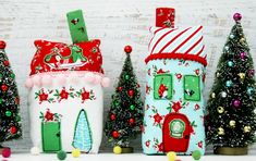 three small houses are decorated with christmas trees and ornaments on the shelf next to each other