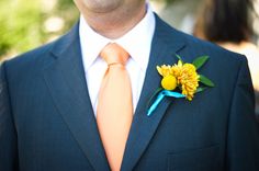 a man wearing a suit and tie with a flower on his lapel pin in front of him