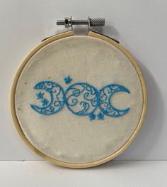 an embroidered hoop with the word boo written in blue on it, sitting next to a white wall