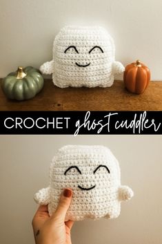 the crochet ghost is sitting next to two pumpkins