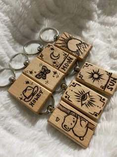 four wooden keychains with designs on them sitting on a white furnishing