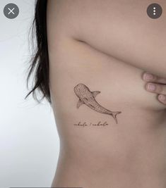 a woman's stomach with a small whale tattoo on her left side ribcage