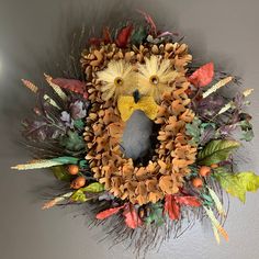 a wreath made out of pine cones and leaves with a stuffed animal in the middle