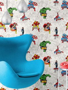 a blue egg chair sitting in front of a wall with superheros on it