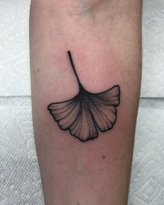 a black and white ginknife tattoo on the left calf area, it looks like a leaf