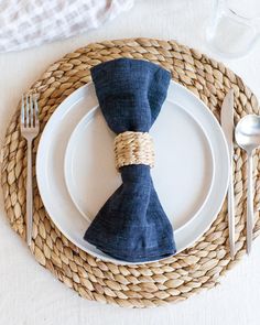 a place setting with blue napkins and silverware on a wicker place mat