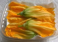 some yellow flowers in a plastic container on a table