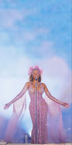 a woman in a pink dress on stage with a microphone