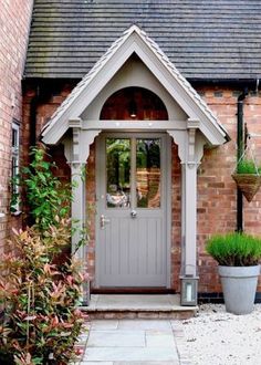 a grey front door with two potted plants