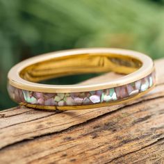 two wedding bands with mother's day flowers on them sitting on a piece of wood