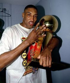 a man holding a trophy in his right hand and wearing a white t - shirt