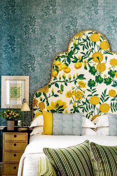 a bed with yellow flowers and green leaves on the headboard in a blue room