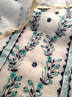 blue and white embroidered fabric with floral designs on it's edges, sitting on a table